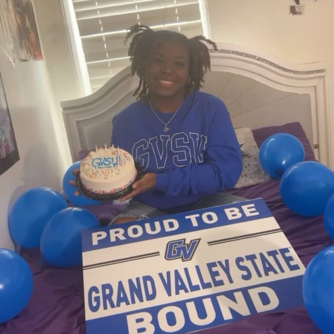 student in GVSU sweatshirt with GVSU cake